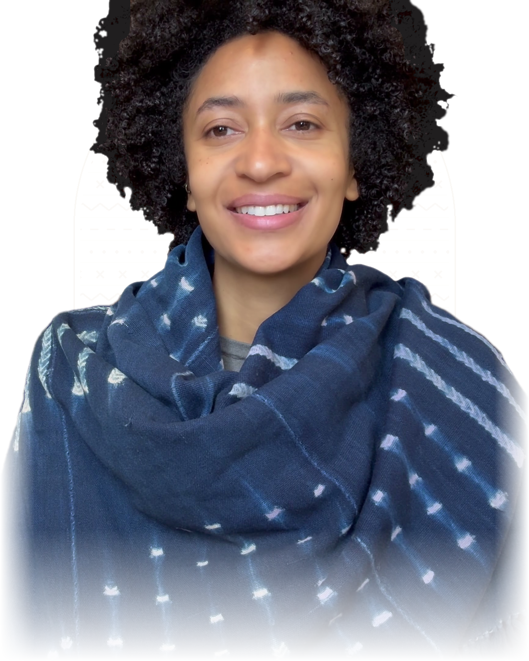 Moyo, founder of Living Earth Yoga, with a wide smile, wrapped in an indigo scarf, in front of a faint mud-cloth pattern